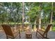 Relaxing outdoor back porch boasting two wooden rocking chairs and a stunning wooded golf course view at 2217 Ramsay St, Charleston, SC 29412