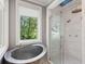 Corner of bathroom with soaking tub and glass door shower; view of greenery from window at 2217 Ramsay St, Charleston, SC 29412