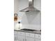 Modern kitchen with stainless steel hood and herringbone tile backsplash above granite counters at 2217 Ramsay St, Charleston, SC 29412