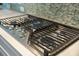 Gas stovetop with black grates and stainless steel knobs, set against a backdrop of a patterned backsplash at 2981 Sturbridge Rd, Mount Pleasant, SC 29466
