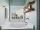 Inviting bathroom with soaking tub, decorative shelves, and large window for natural light at 3807 Canary Ct, North Charleston, SC 29420