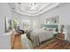 Airy bedroom showcasing tray ceilings, hardwood floors, a ceiling fan, and many windows at 3872 James Bay Road, Johns Island, SC 29455