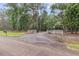 Gravel driveway with a white fence entrance leads to a secluded property surrounded by lush greenery and mature trees at 4352 Park Island Rd, Hollywood, SC 29449