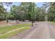View of the driveway leading to the property, framed by trees and a white fence at 4352 Park Island Rd, Hollywood, SC 29449