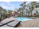 Backyard pool area with lounge chairs and a charming red home in a fenced landscaped yard at 4352 Park Island Rd, Hollywood, SC 29449