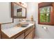 Bathroom with decorative mirror, bowl sink, wood cabinets, and a bright window at 6464 Saint Anthony Dr, Meggett, SC 29449