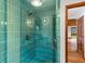 Modern shower with turquoise tiles, glass enclosure, a rainfall shower head and wood accents at 6464 Saint Anthony Dr, Meggett, SC 29449