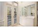 Vanity with white cabinets, gold fixtures and a large beveled mirror with french doors at 74 Hospitality St, Mount Pleasant, SC 29464