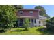 Two-story home with a screened-in porch, red siding, and a metal roof partially obscured by vegetation at 116 Stillfield Dr, Moncks Corner, SC 29461