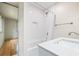 Bright bathroom featuring a white tiled shower and modern fixtures, complemented by hardwood floors in an adjacent room at 1203 Forestwood Dr, Charleston, SC 29407
