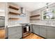 Beautiful kitchen with gray cabinets, stainless steel range hood, open wood shelves, and a stylish patterned backsplash at 1203 Forestwood Dr, Charleston, SC 29407