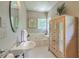 Bright bathroom with a pedestal sink, soaking tub, and wood armoire at 1343 Headquarters Plantation Dr, Johns Island, SC 29455