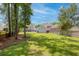 Green backyard with a fire pit, screened in porch, surrounded by lush trees, and a privacy fence at 1666 Sparkleberry Ln, Johns Island, SC 29455