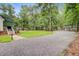 Gravel driveway leading to a charming home amidst a verdant landscape, and outbuildings at 196 Dogwood Ridge Rd, Summerville, SC 29485