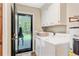 Bright laundry room with white washer and dryer, cabinets, and backyard access at 196 Dogwood Ridge Rd, Summerville, SC 29485