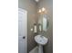 A compact powder room with pedestal sink, wall mirror, and classic finishes at 3012 Candela Grove Dr, Charleston, SC 29414