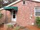 Charming brick home with a green awning over the front door and wrought iron details at 3034 Maybank Hwy, Johns Island, SC 29455