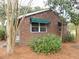 Charming brick house with green awnings, surrounded by lush greenery and natural pine straw landscape at 3034 Maybank Hwy, Johns Island, SC 29455