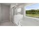 Well-lit bathroom with a tub and an outdoor view from a large window at 7011 Pumpkinseed Dr, Johns Island, SC 29455