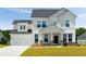 Charming two-story home featuring a two-car garage, inviting porch, and manicured lawn at 7011 Pumpkinseed Dr, Johns Island, SC 29455