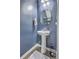 Stylish half bathroom featuring a pedestal sink, a round mirror, and modern fixtures, maximizing space and functionality at 9101 Parlor Dr, Ladson, SC 29456