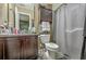 Bathroom with a granite countertop vanity, decorative mirror, shower with curtain, toilet, and cabinet above it at 9101 Parlor Dr, Ladson, SC 29456