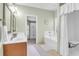Bright bathroom featuring a double sink vanity, soaking tub, and accessible shower with curtain and built-in seat at 9133 Markleys Grove Blvd, Summerville, SC 29485
