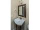 Compact bathroom features a corner sink with dark wood vanity and framed mirror at 9305 Sweetbay Ct, Ladson, SC 29456