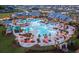 Stunning aerial view of a resort-style community pool, with palm trees, lounge chairs, umbrellas and a clubhouse in the background at 99 French Garden Cir, Summerville, SC 29486