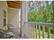 A well-lit outdoor balcony with two chairs and a table that overlooks a green wooded area at 1300 Park West Blvd # 519, Mount Pleasant, SC 29466