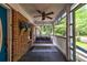 Charming front porch features a brick wall, porch swing and fan, with a striped rug at 1384 Tibwin Rd, McClellanville, SC 29458