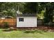 White backyard shed with a window, nestled in a well-manicured lawn with mature trees at 1417 Downing St, Charleston, SC 29407