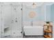 Bright bathroom featuring marble tile, a glass shower, and a standalone soaking tub at 2369 Rice Pond Rd, Charleston, SC 29414