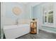 Bright bathroom featuring a standalone soaking tub, shuttered windows, and light blue walls at 2369 Rice Pond Rd, Charleston, SC 29414