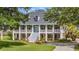 Beautiful two-story home featuring a double porch, lush lawn, and a circular driveway framed by mature trees at 2369 Rice Pond Rd, Charleston, SC 29414