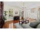Bright living room with hardwood floors, piano, fireplace, and staircase with decorative chandelier at 2369 Rice Pond Rd, Charleston, SC 29414