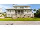 Inviting two-story beach home featuring a covered porch and manicured lawn at 2618 Raven Dr, Sullivans Island, SC 29482