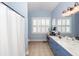 Bright bathroom with blue vanity, white shutters, and shower with curtain at 2632 Alderly Ln, Mount Pleasant, SC 29466