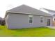 View of the backyard and exterior of the home with two windows and sliding glass doors at 303 Citation Way, Moncks Corner, SC 29461