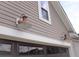 Close up of garage exterior shows dark brown door flanked by copper-toned sconces and light gray siding at 303 Citation Way, Moncks Corner, SC 29461