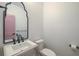 Stylish powder room featuring a decorative mirror, elegant sink, and toilet at 4374 Cotton Flat Rd, Summerville, SC 29485