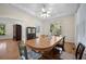 Bright dining area with an oval wooden table, ceiling fan, and multiple windows overlooking greenery at 6385 Shilelagh Oaks Pkwy, Ravenel, SC 29470