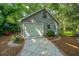 Charming gray garage with a white door surrounded by beautiful lush trees and landscaping at 802 Robert E. Lee Blvd, Charleston, SC 29412