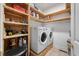 Well-organized laundry room with washer, dryer, and shelving for storage at 8320 Tyrian Path, North Charleston, SC 29418