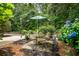 Charming outdoor patio with a table, chairs, and umbrella nestled amongst lush greenery and hydrangeas at 907 High Nest Ln, Charleston, SC 29412
