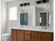 Bathroom with double sinks, wood cabinets, vanity lighting, and a large mirror at 9255 Ayscough Rd, Summerville, SC 29485