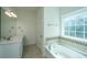 Bright bathroom featuring a soaking tub with decorative tile surround and a vanity with double sinks at 9710 Table Mountain Ln, Ladson, SC 29456