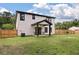 The two-story home has a covered patio and sits on a grassy lot with a wood fence at 1000 Retreat Ave, Moncks Corner, SC 29461