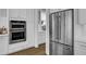 Stainless steel refrigerator and built-in ovens complemented by white cabinetry in this modern kitchen at 1098 Reserve Ln, Awendaw, SC 29429