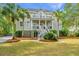 Inviting two-story home featuring double porches, complemented by lush landscaping and mature palm trees at 1143 Sea Eagle Watch, Charleston, SC 29412